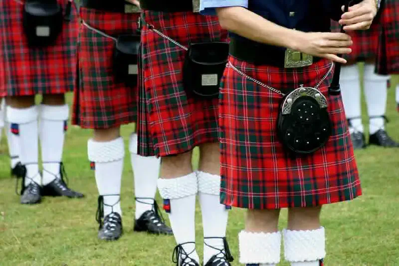Pipe band members wearing red tartan kilts